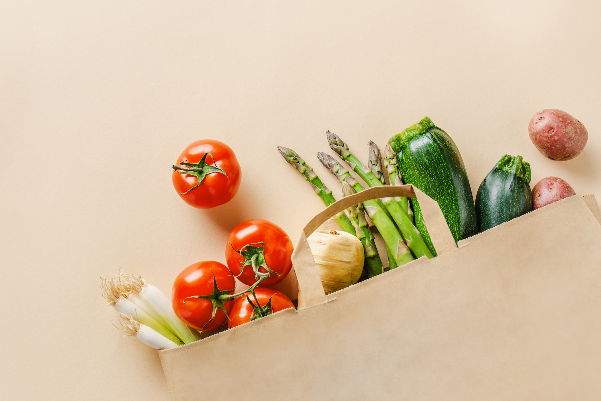 Different vegetables in paper bag on beige