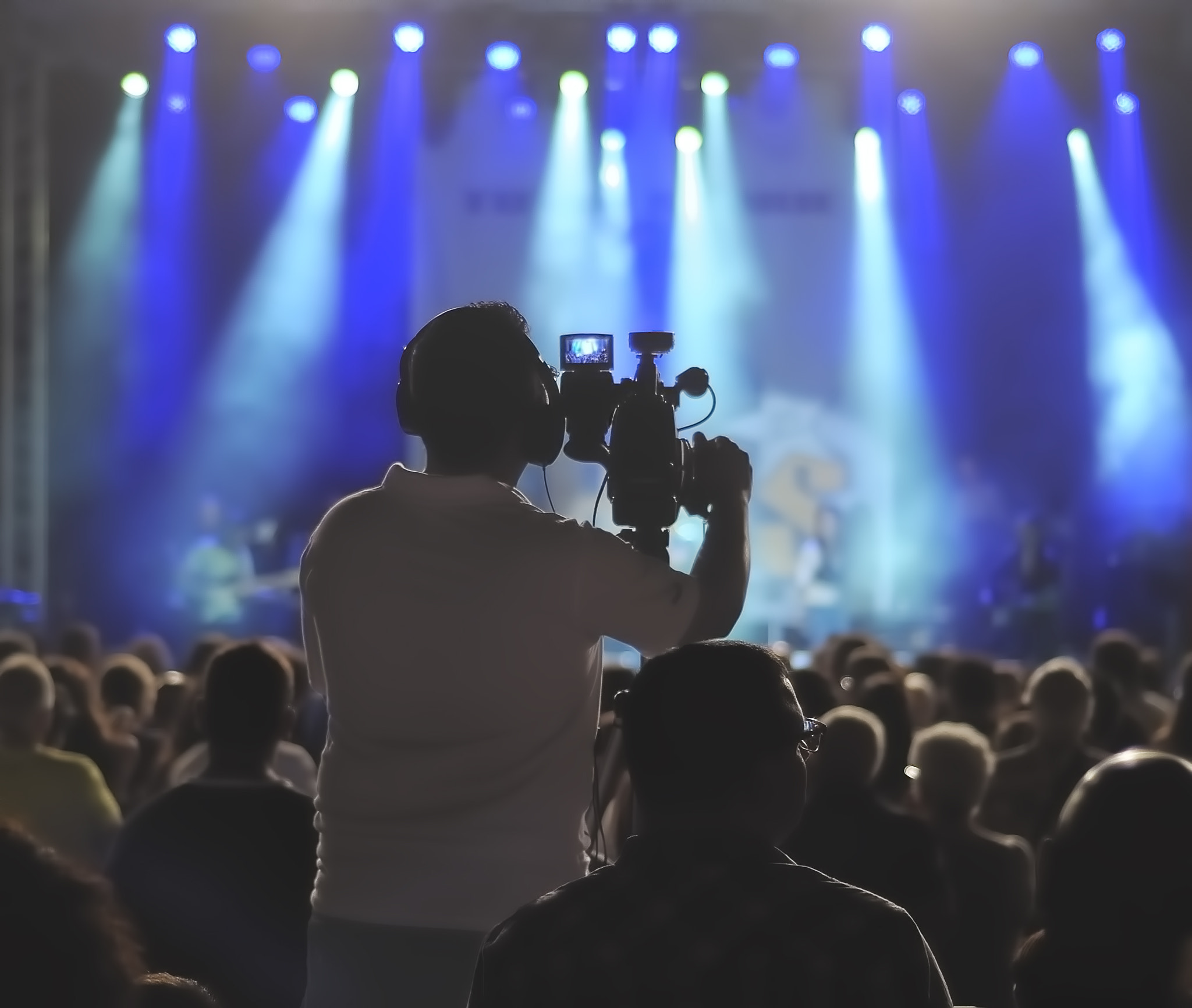 Cameraman silhouette on a concert stage. Visible noise due high ISO, soft focus, shallow DOF,...