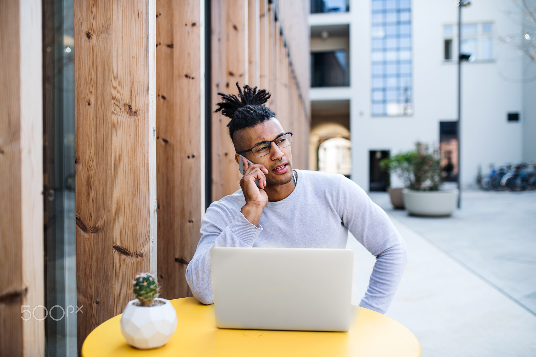 Young businessman with laptop in courtyard, start-up concept.