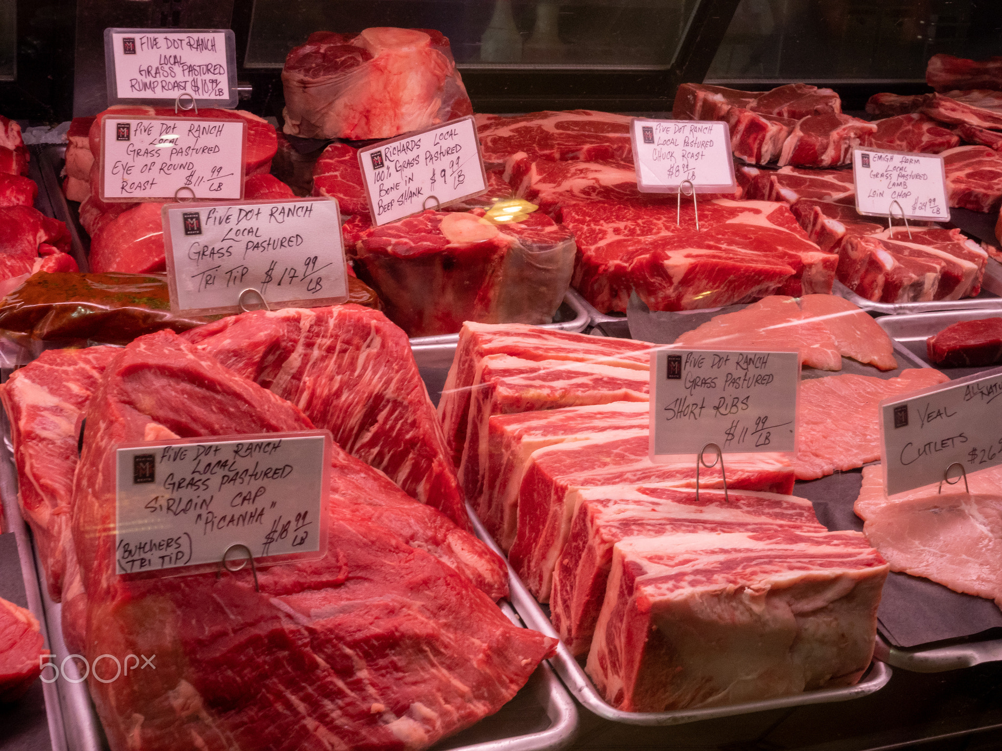 Various cuts of beef and steak behind the glass of a butcher's shop in grocery store