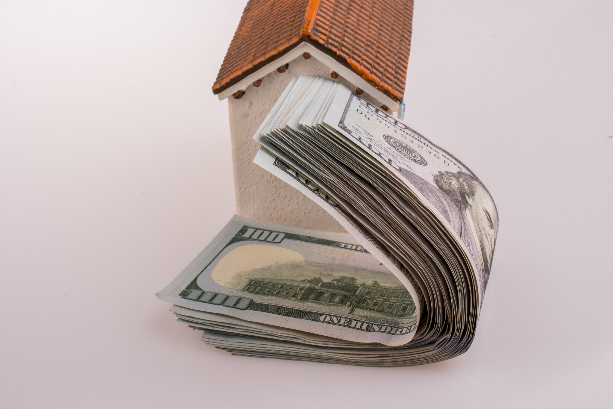 American dollar banknotes by the side of a model house