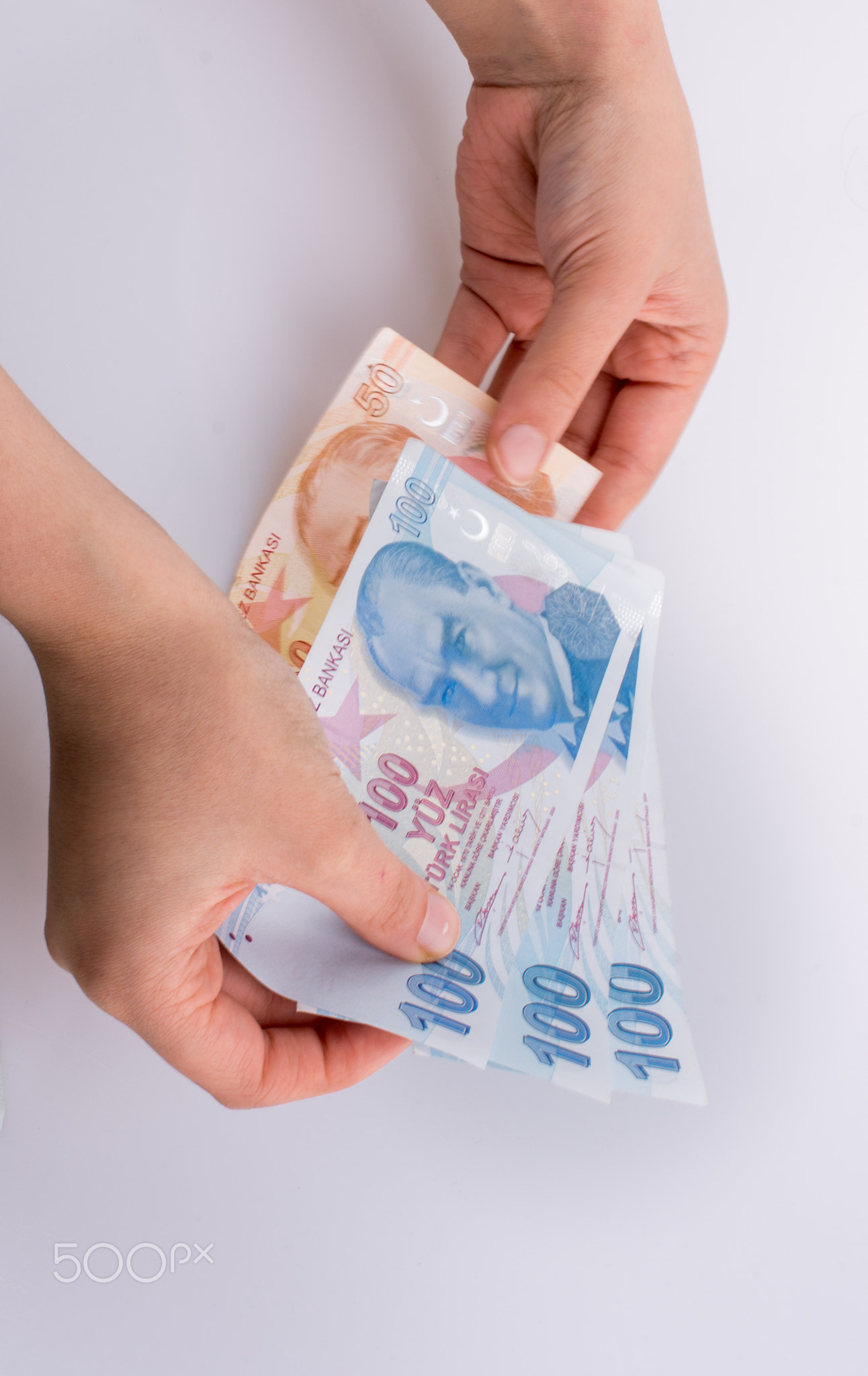 Hands holding Turksh Lira banknotes by the side of American doll