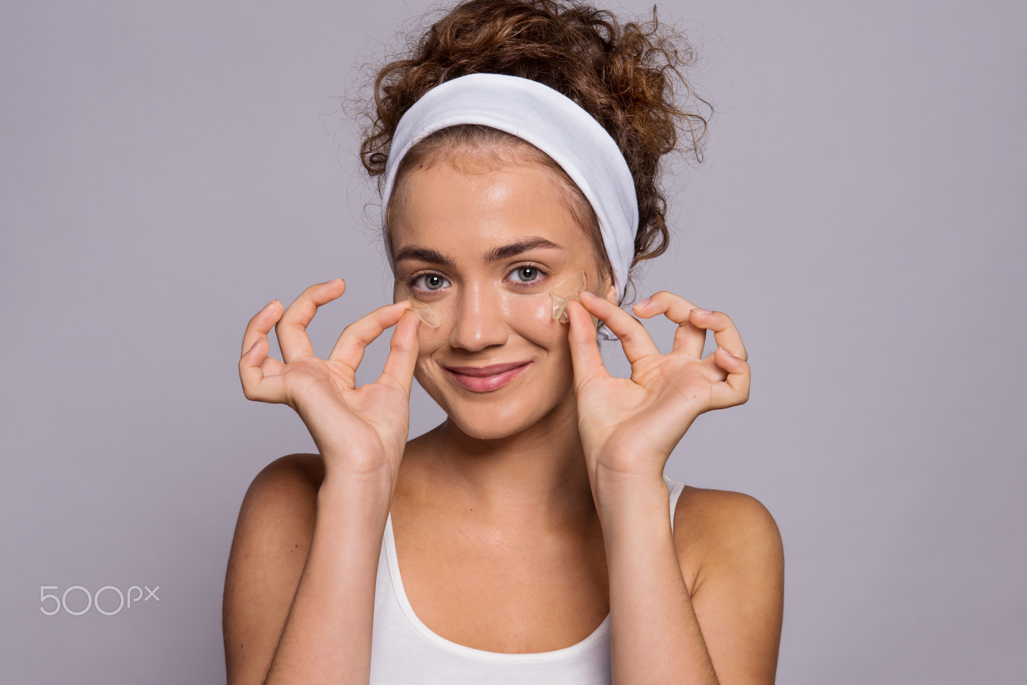 A portrait of a young woman with collagen pads in a studio, beauty and skin care.