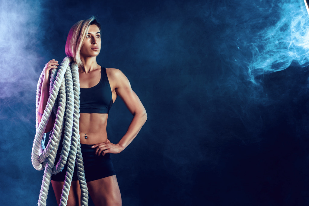 Attractive woman in black sportswear with heavy ropes on her shoulders