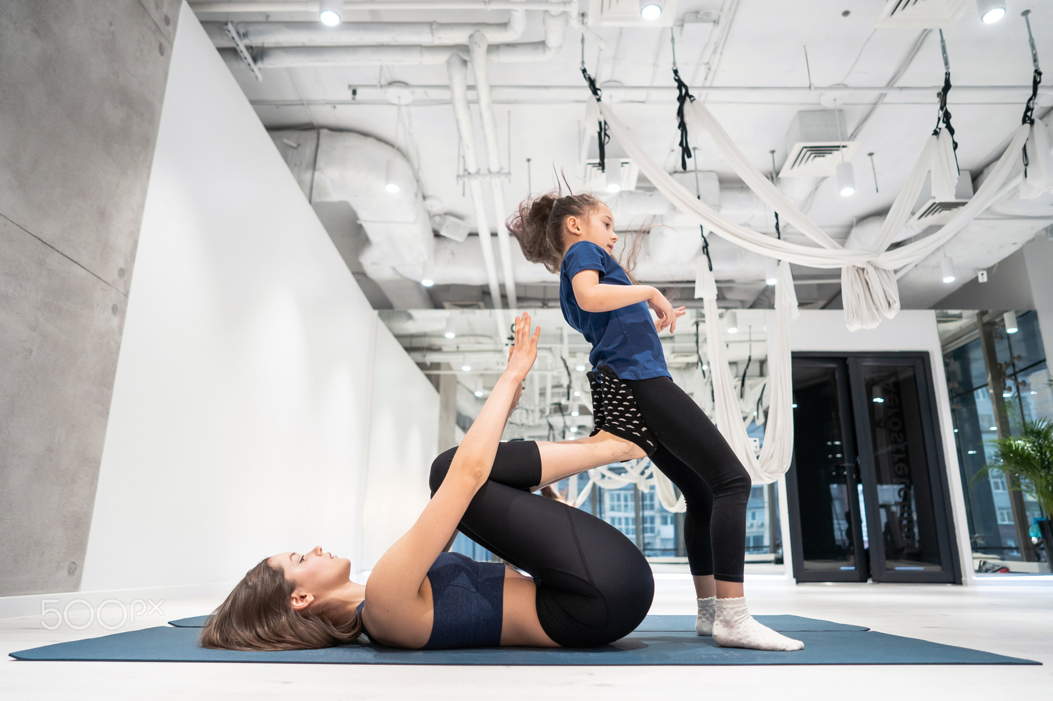 Young adult mother doing fitness with her little daughter