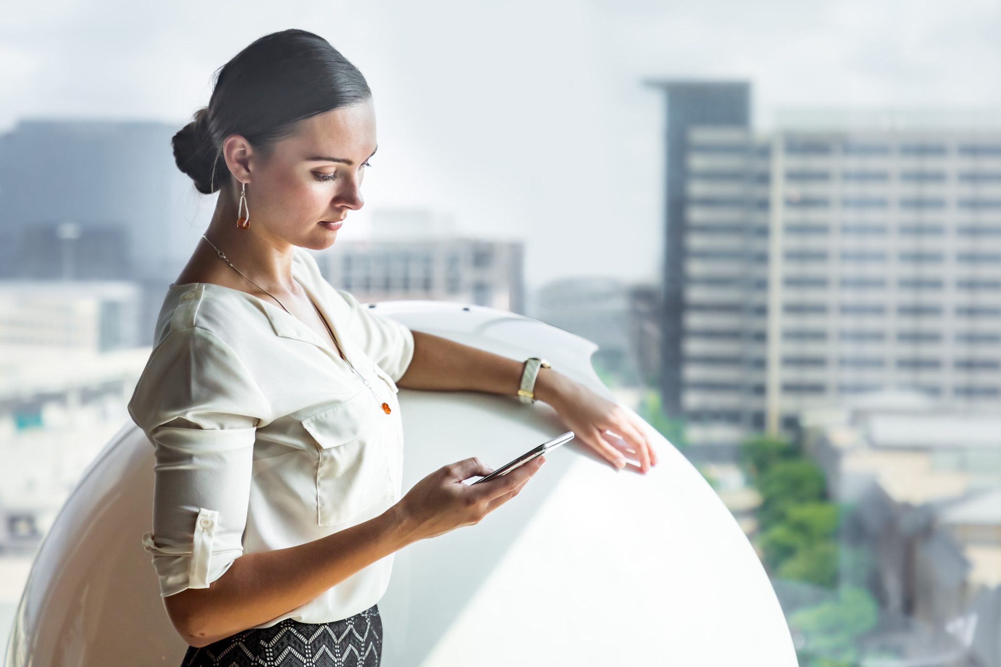 Young businesswoman is checking her phone in a modern office