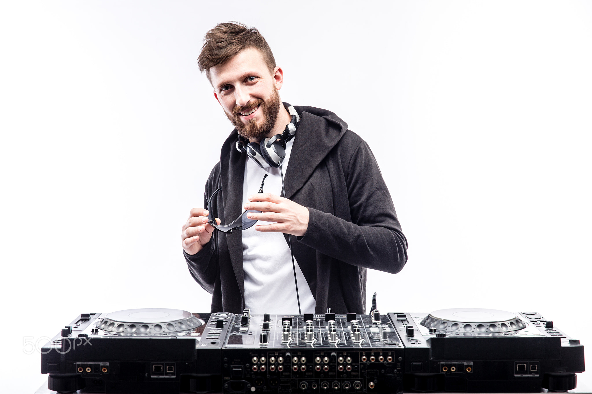 Trendy male dj posing against mixing console