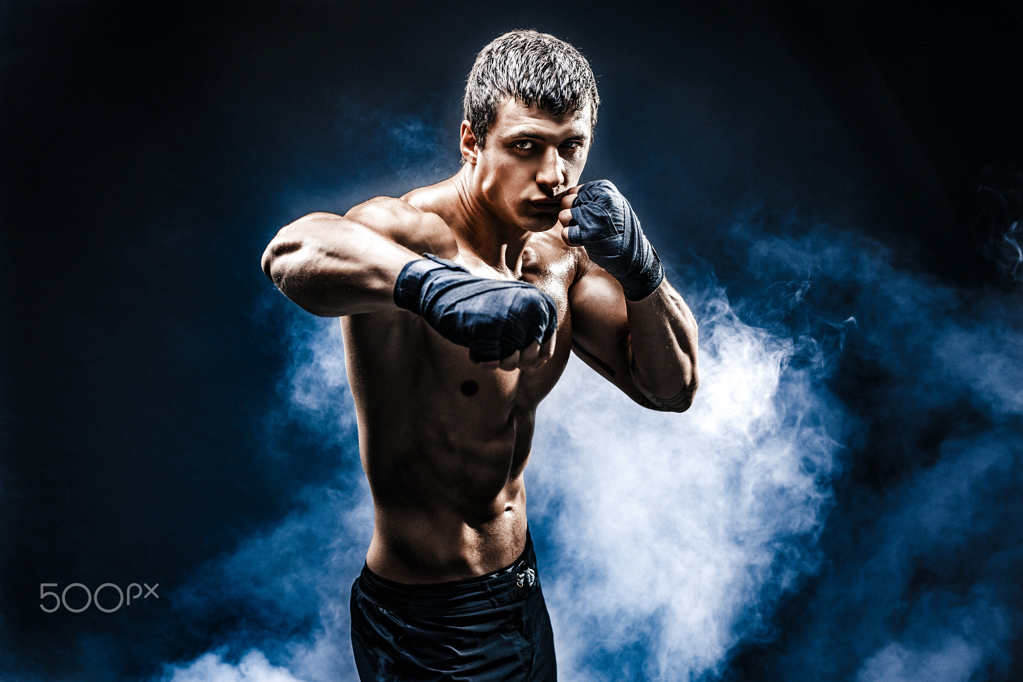 Muscular topless fighter in boxing gloves