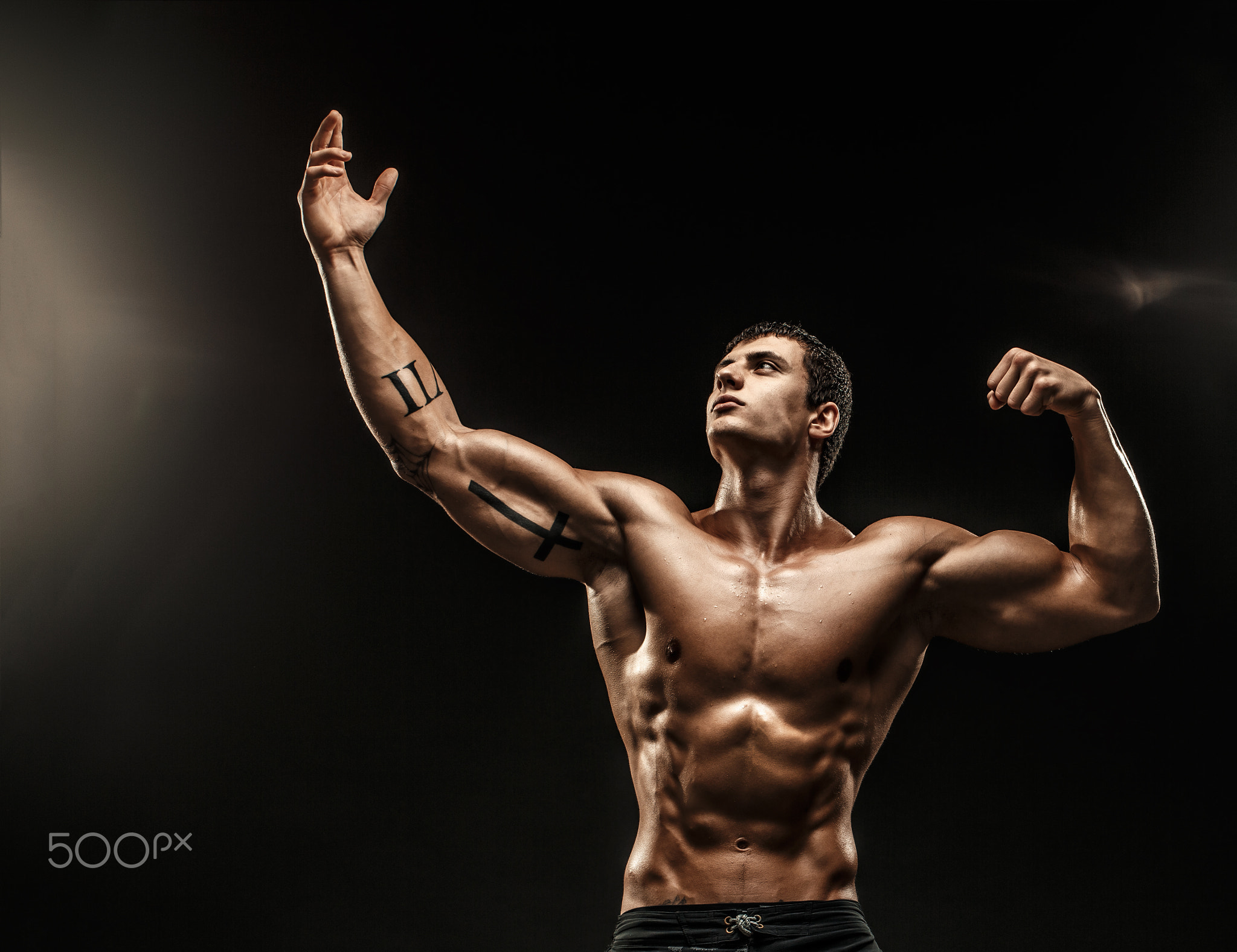 Portrait of shirtless muscular man with arm up