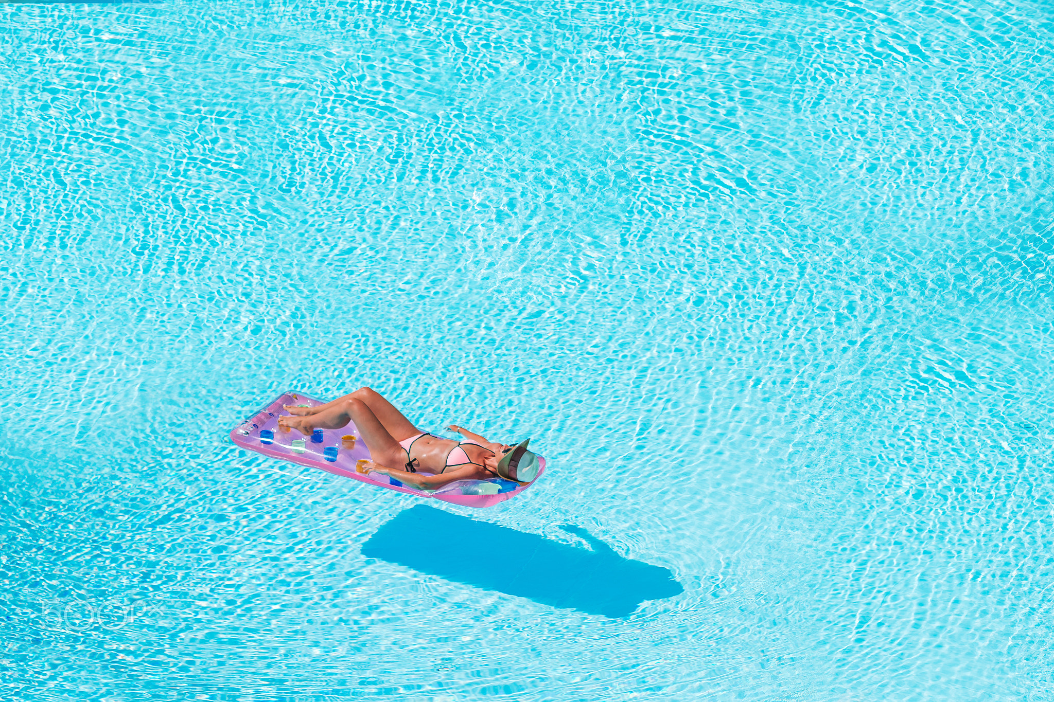 Young woman in bikini air mattress in the big swimming pool