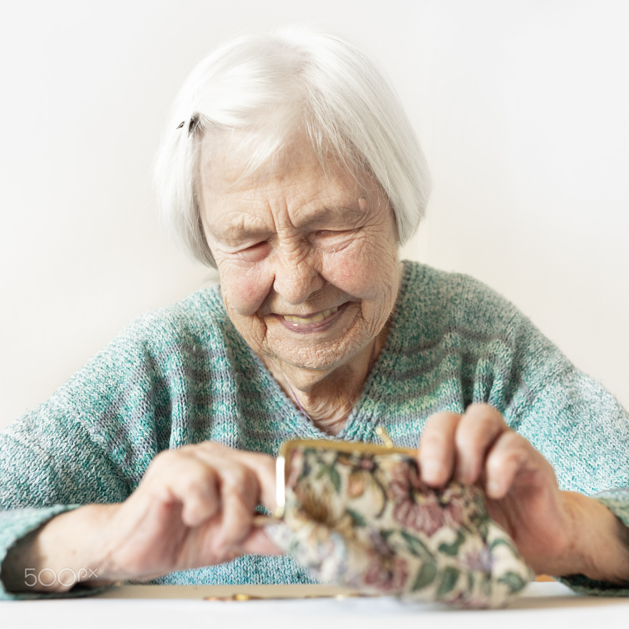 Cheerful elderly 96 years old woman sitting at table at home happy with her pension savings in...