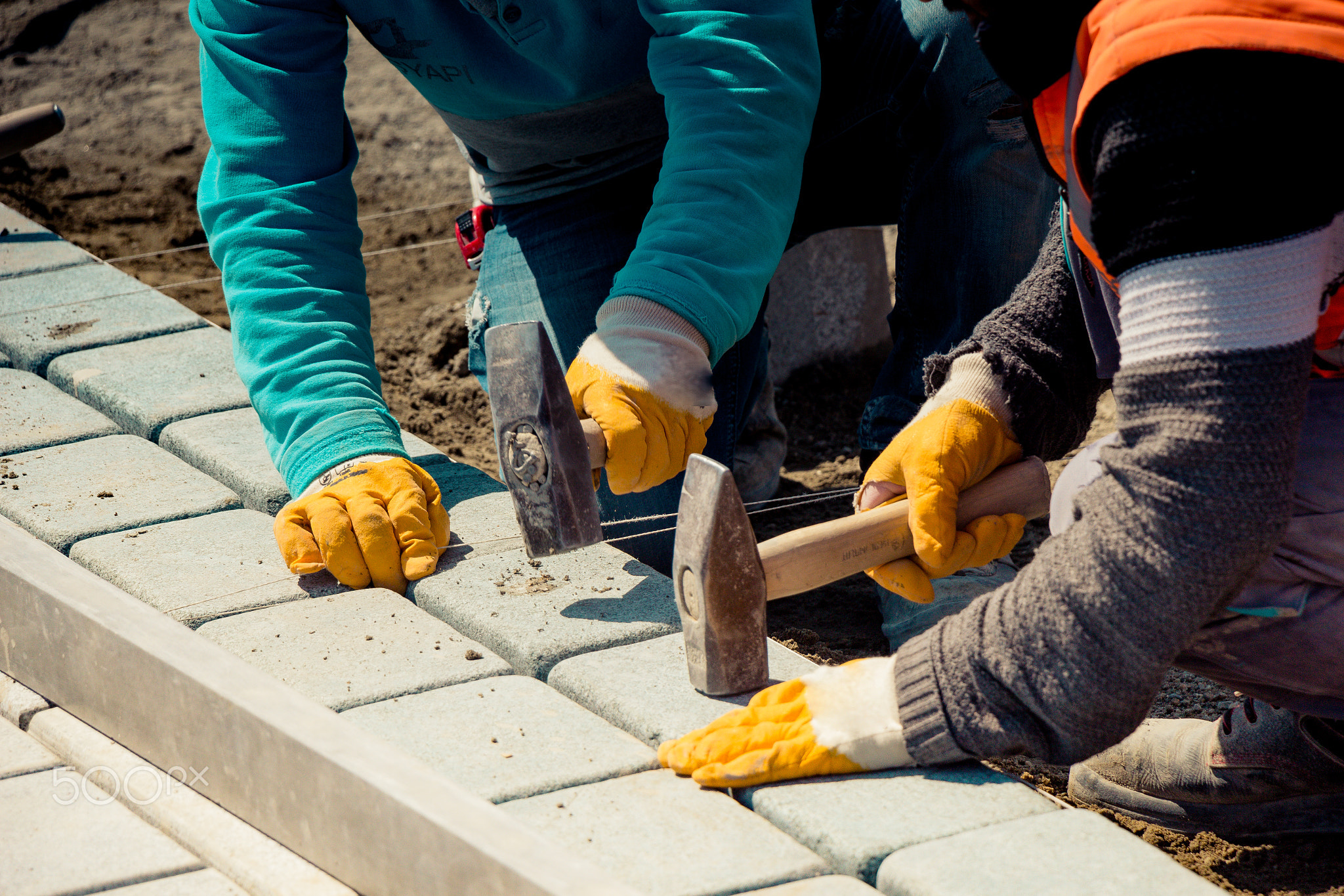 Male hand with brick hammer repairing the pavement