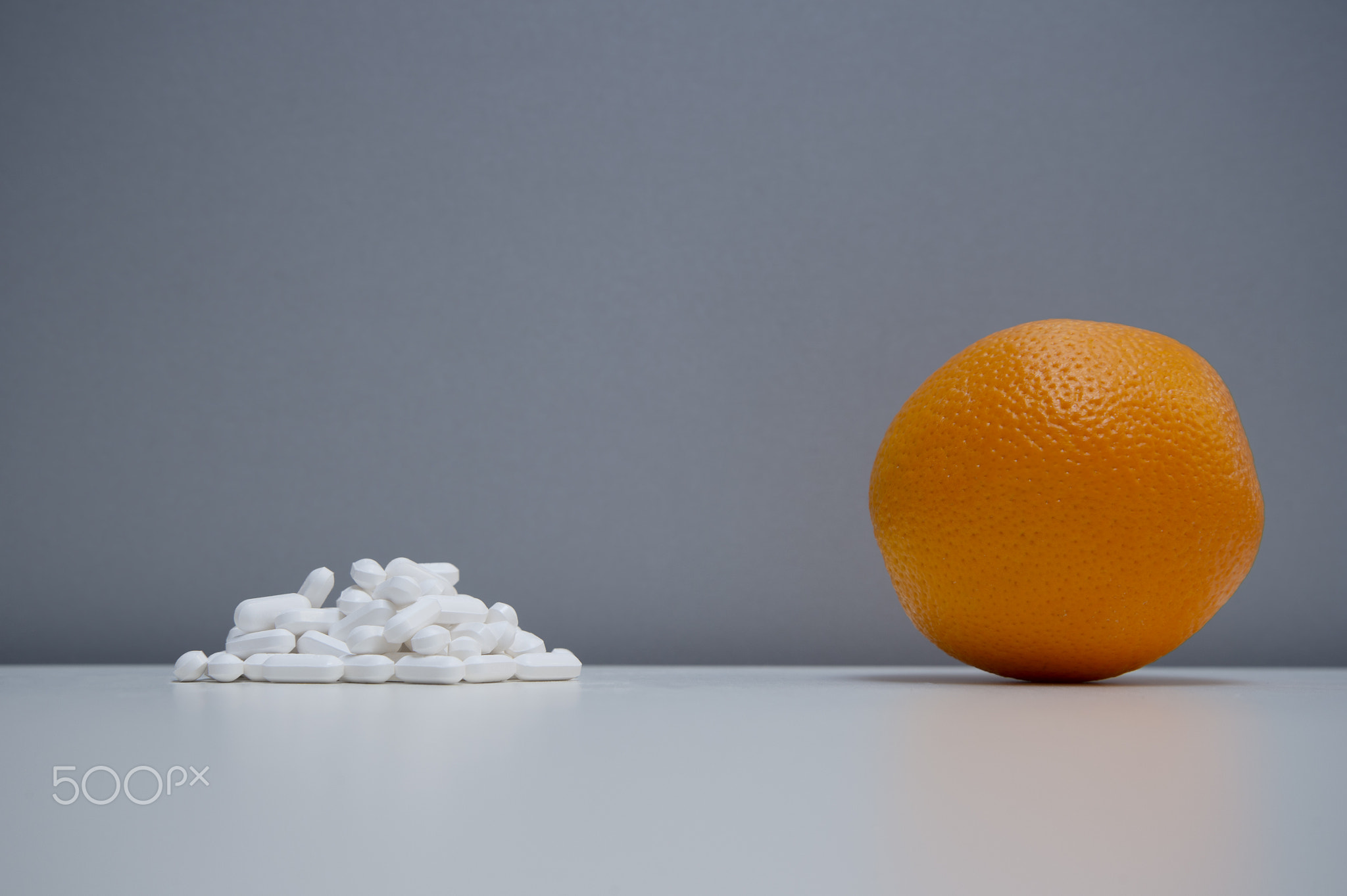 single orange fruit with medical white pill on healthy food ther