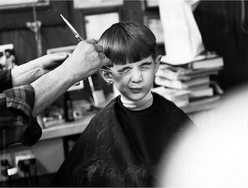 Boy grimaces as he gets a haircut