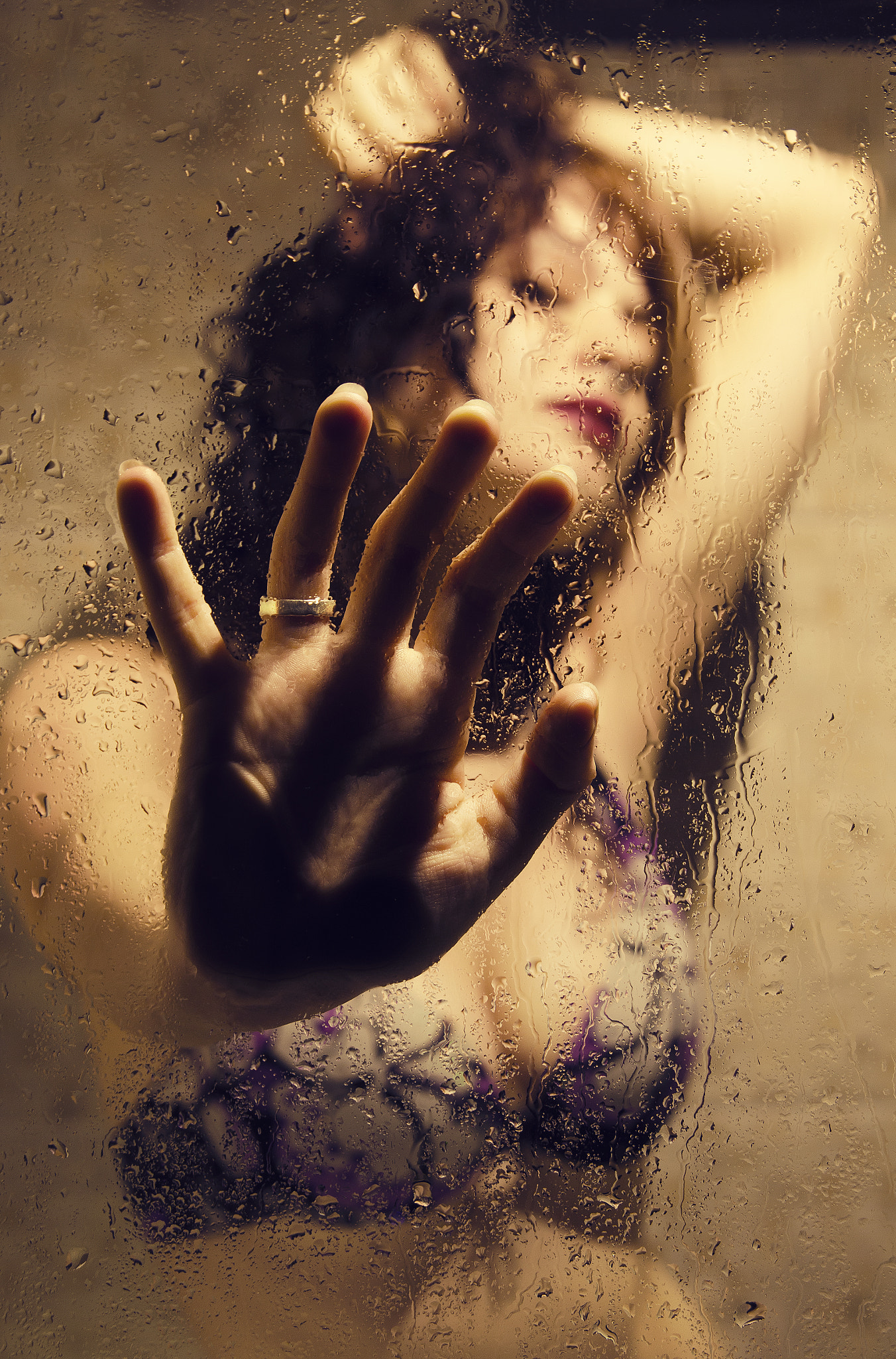 Woman behind glass bathroom stall with hands forward, sensual feeling
