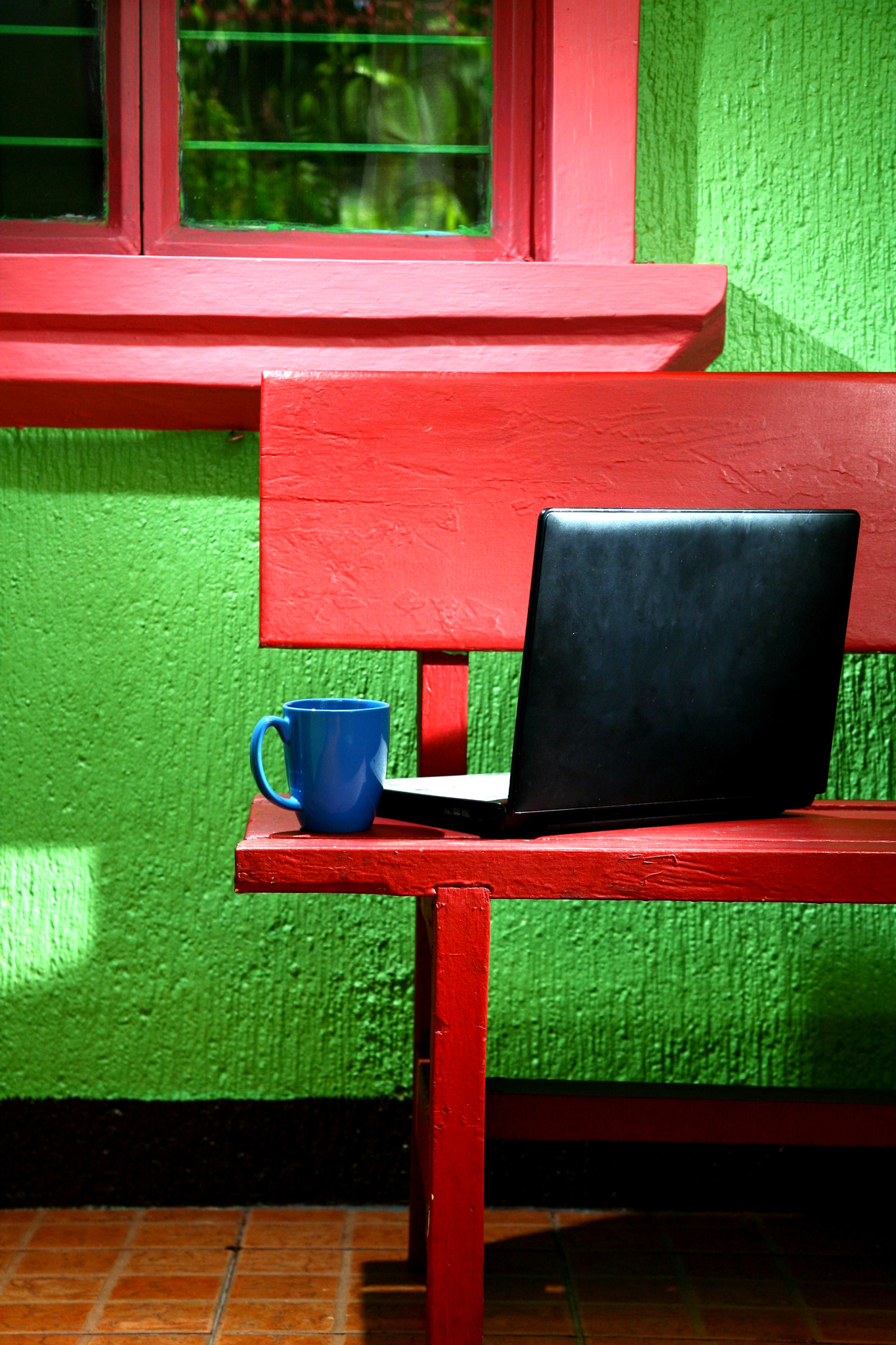 coffee mug and laptop computer on a bench