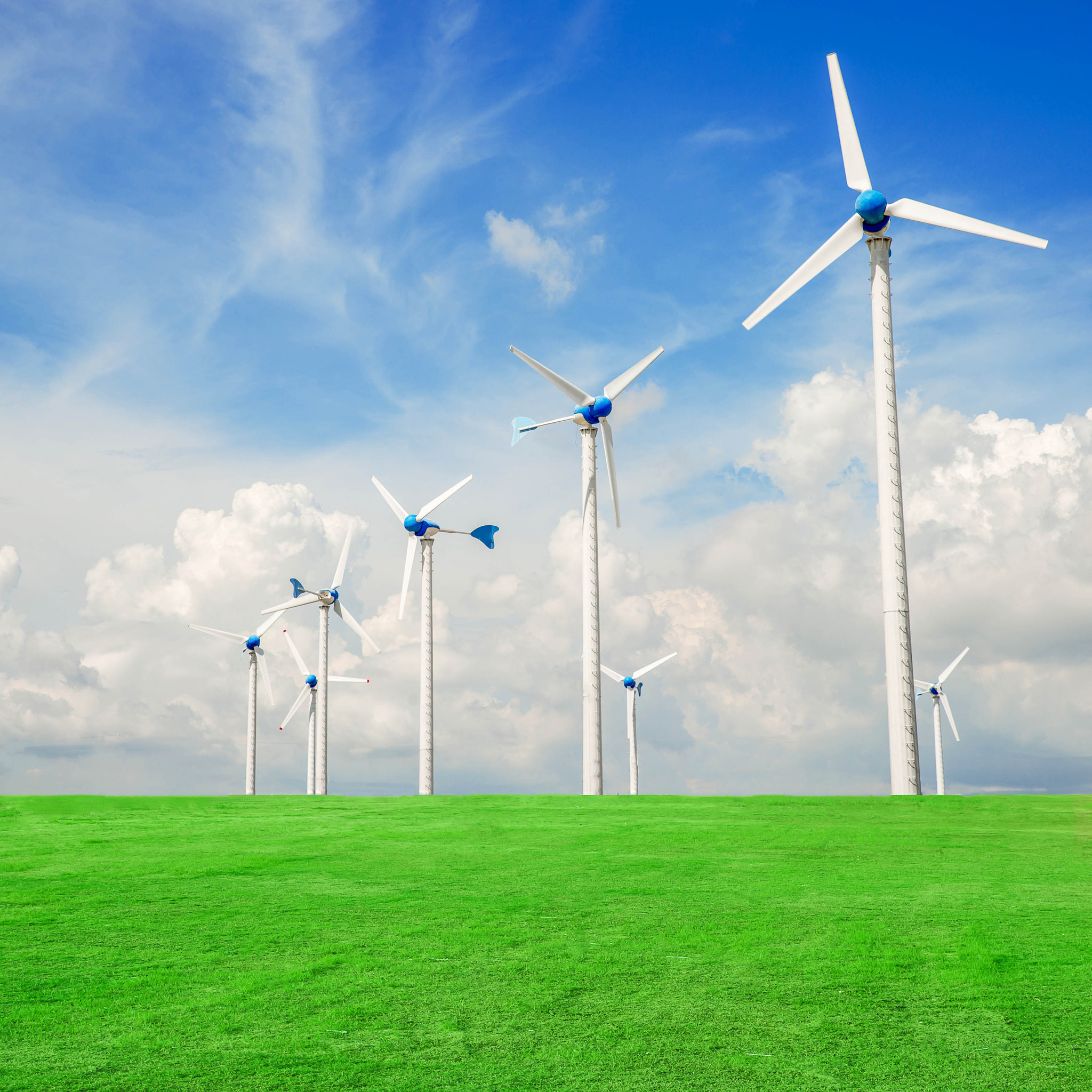 Wind mill power plant in green field  against blue sky