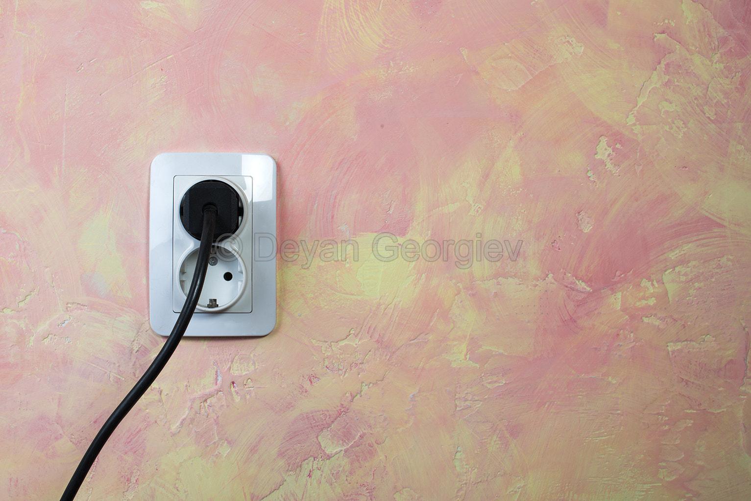 White socket and cable on pink wall.