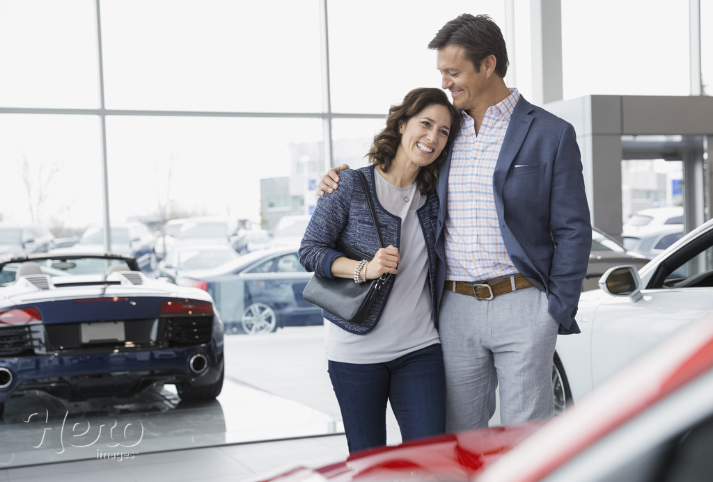 Couple hugging in car dealership showroom