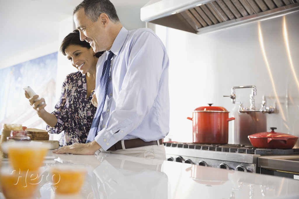 Couple checking smart phone in kitchen