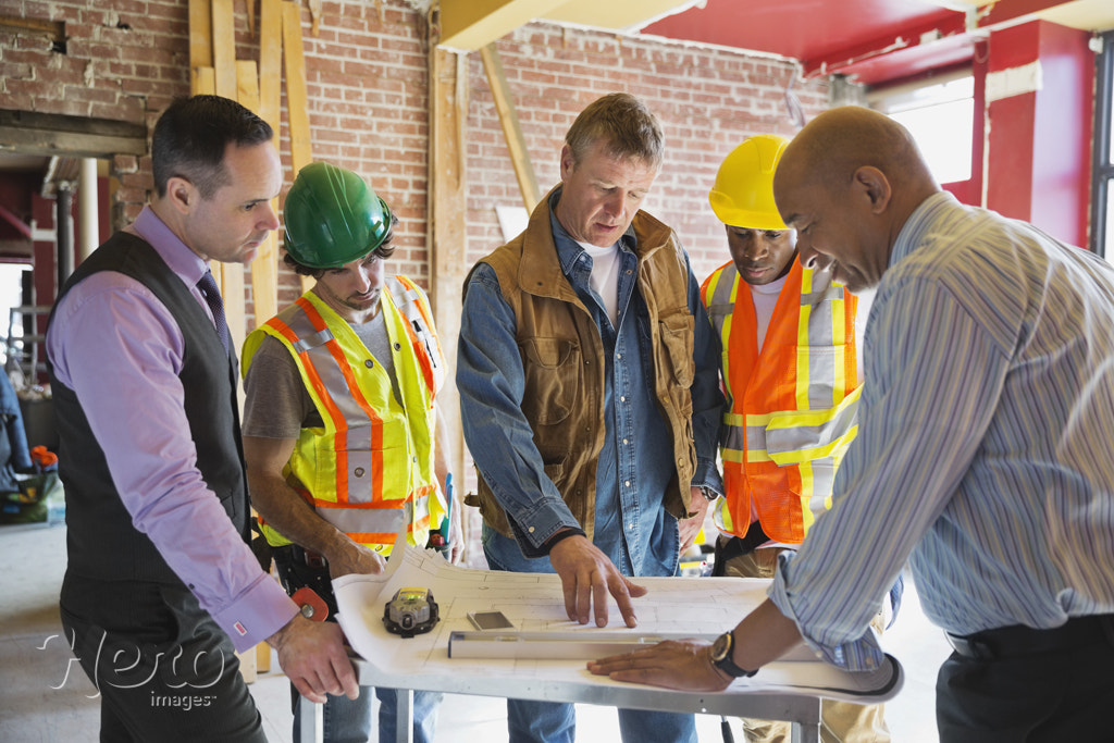 Foreman explaining blueprint to tradesmen at construction site