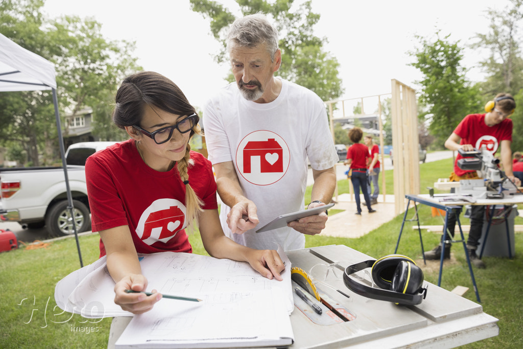 Volunteers reviewing blueprints near construction frame