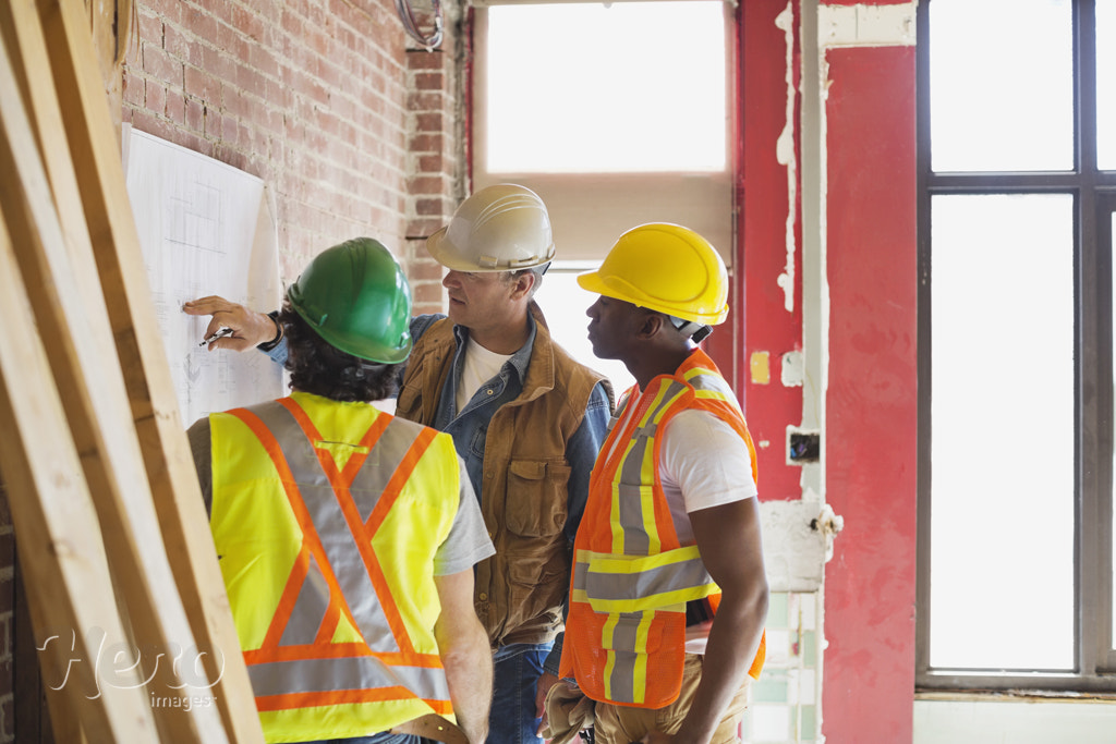 Foreman explaining blueprint to tradesmen at construction site