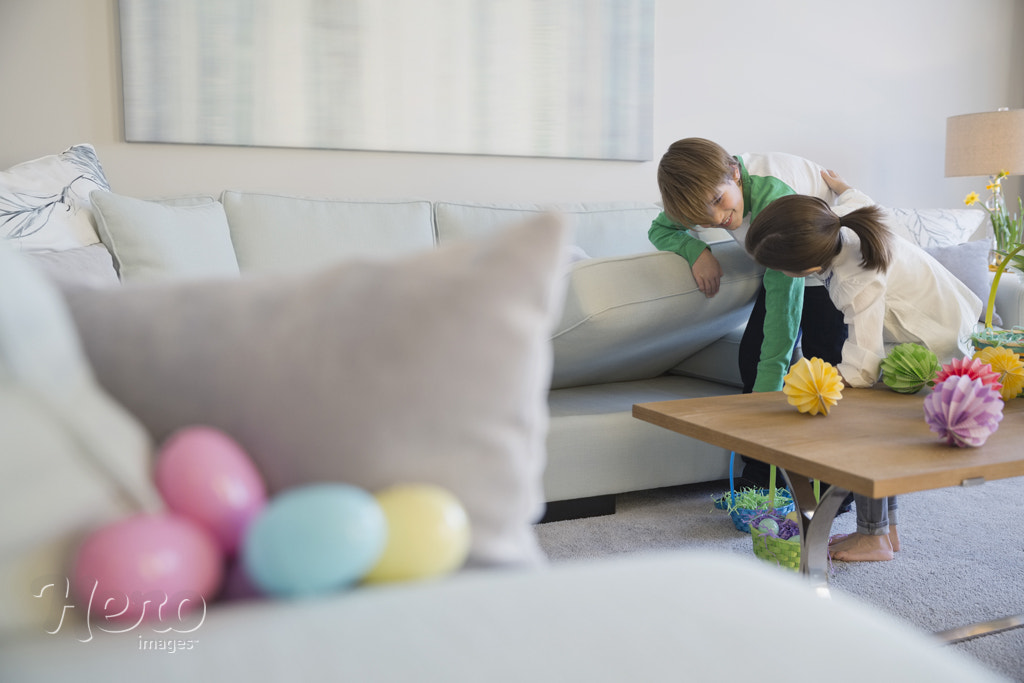 Siblings searching for Easter eggs in living room