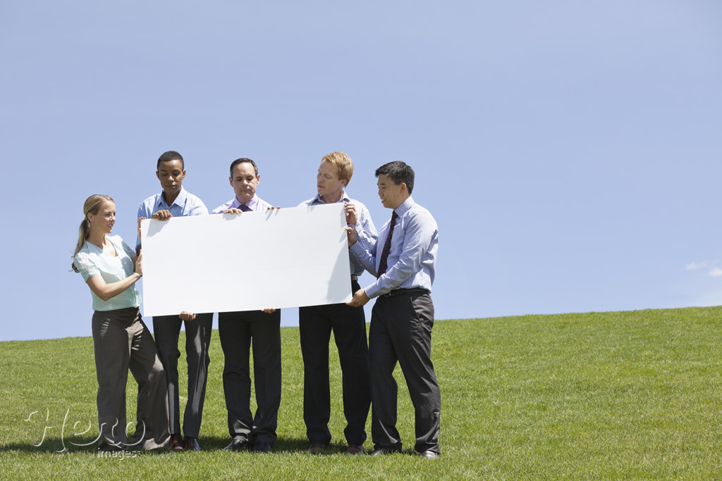 Group of business people displaying blank sign together