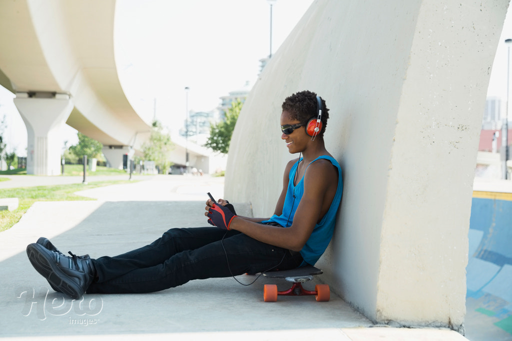 Teenager with cell phone and headphones on skateboard