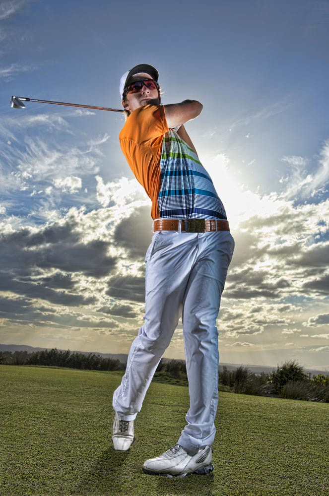 Golfer tees off in late afternoon light