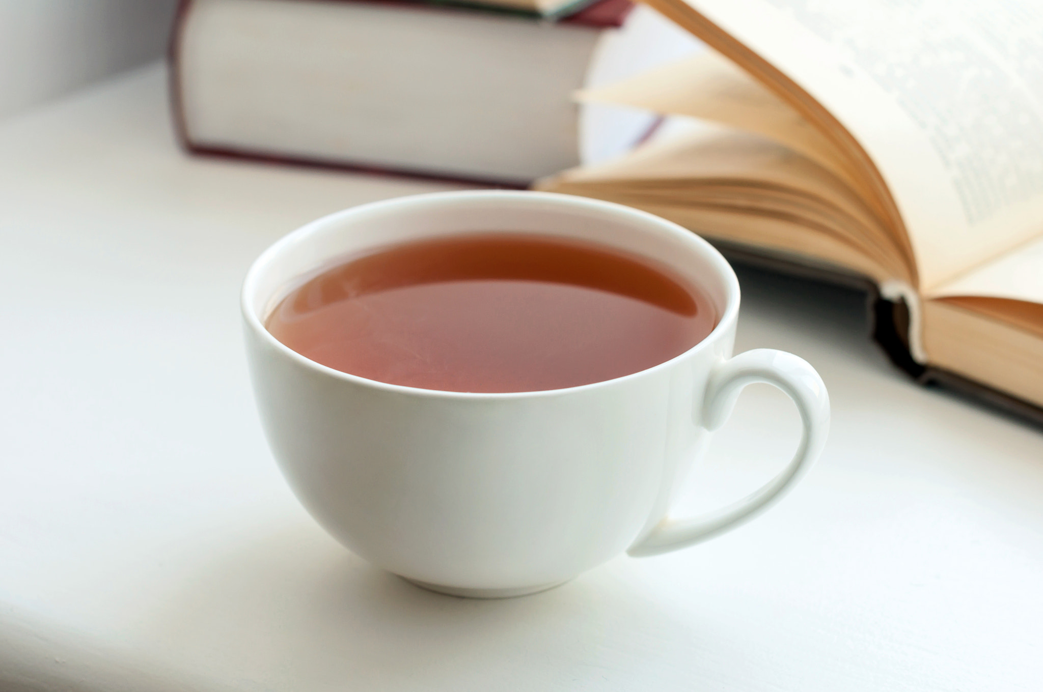 Cup of black tea and some books to read lying on the table