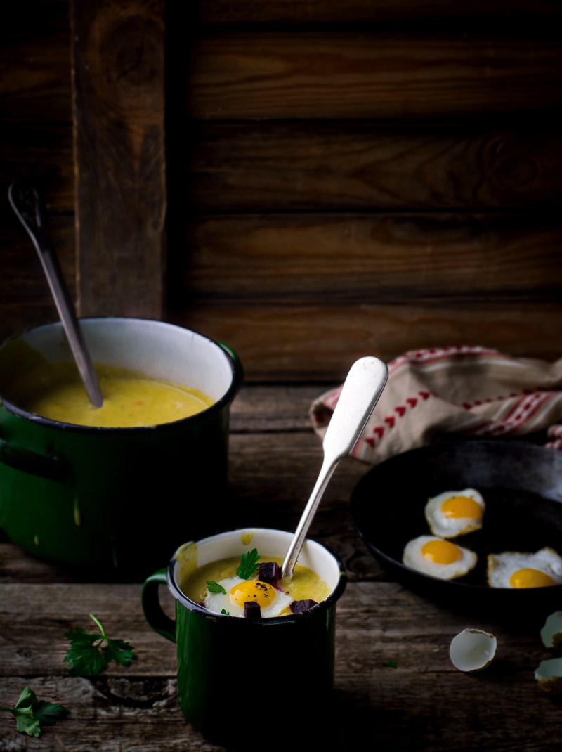 potato soup - mashed potatoes with fried eggs on a rustic background in vintage style.